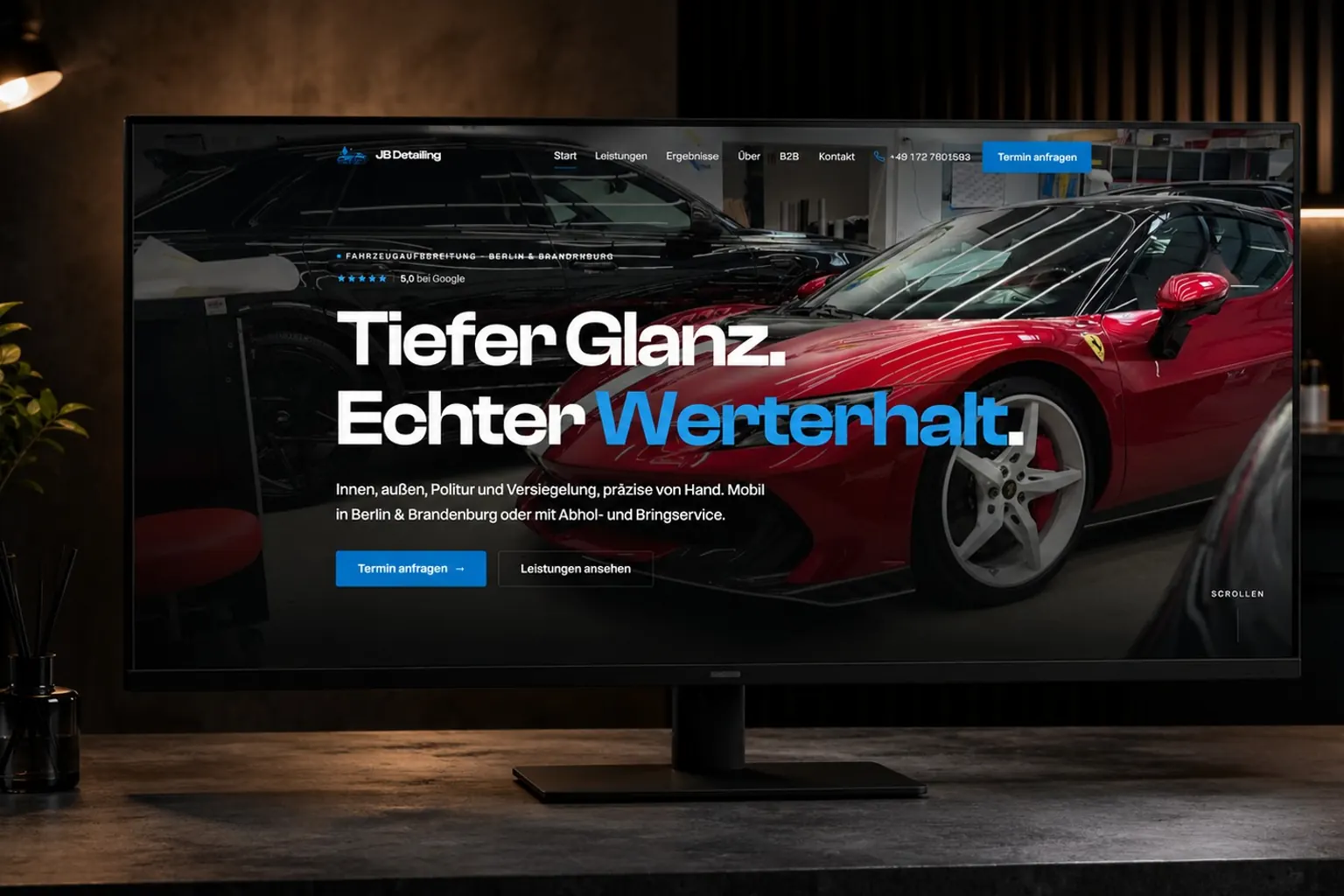 Startseite von JB Detailing auf einem breiten Monitor in einer dunklen Detailing-Werkstatt mit warmem Licht.